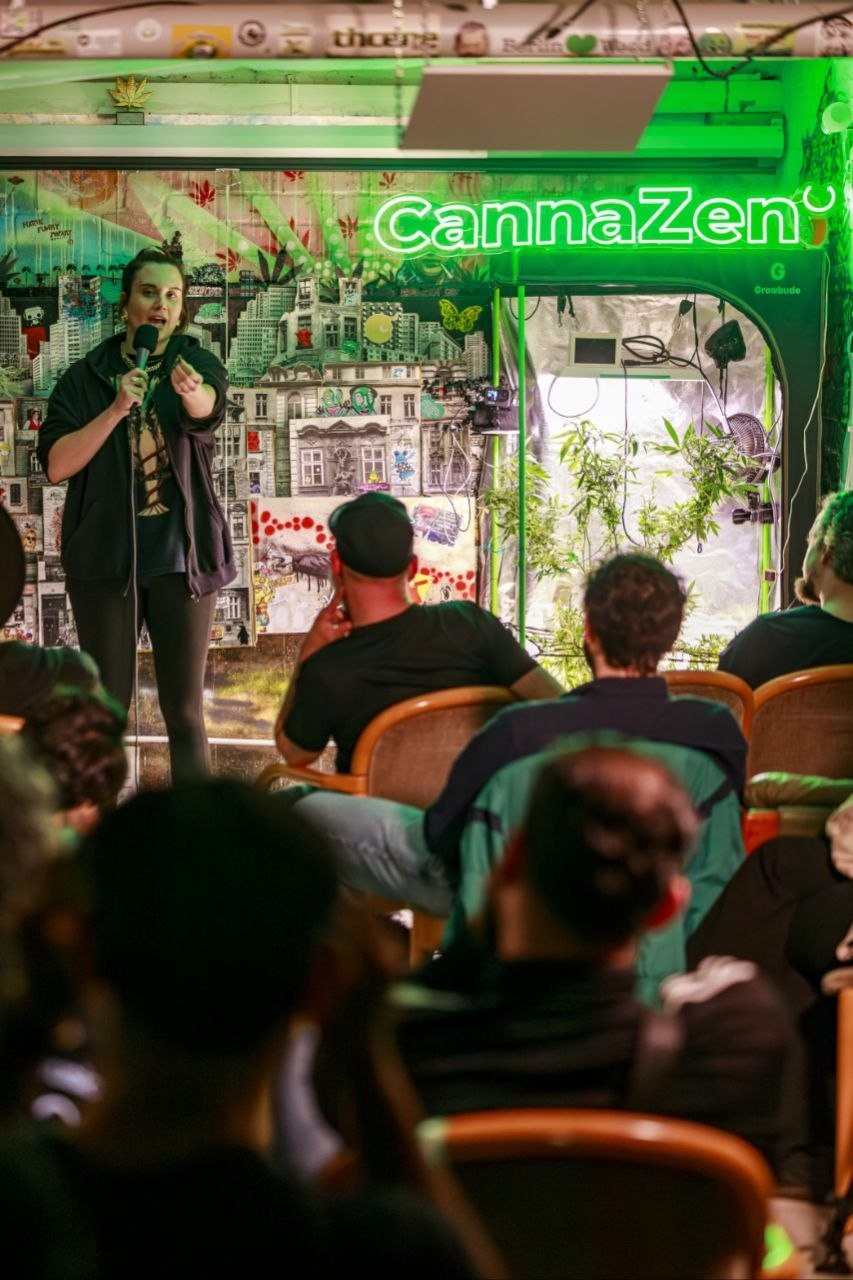 Comedienne in schwarzer Jacke spricht zum Publikum