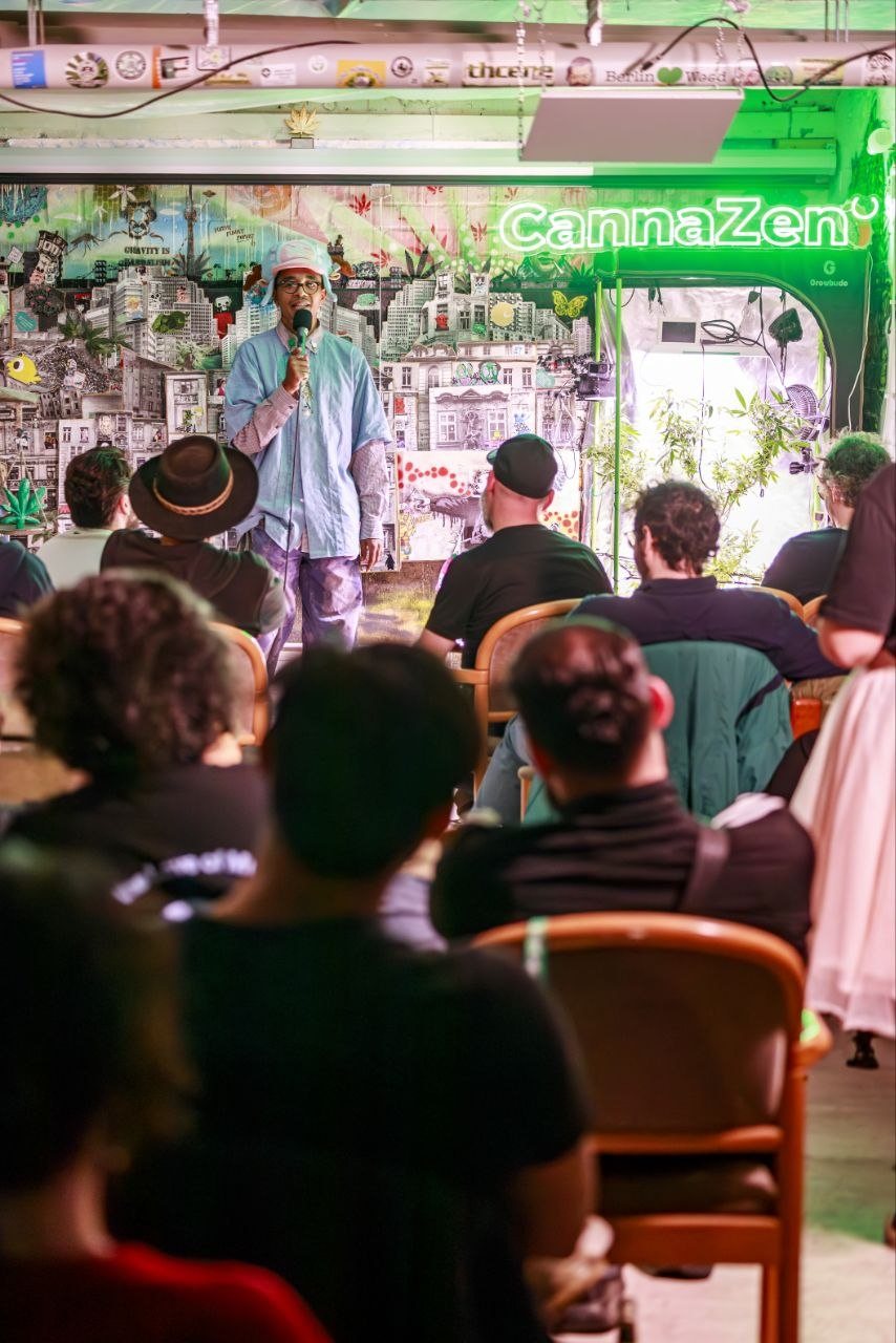Comedian mit Hut und Mikrofon vor vollem Publikum